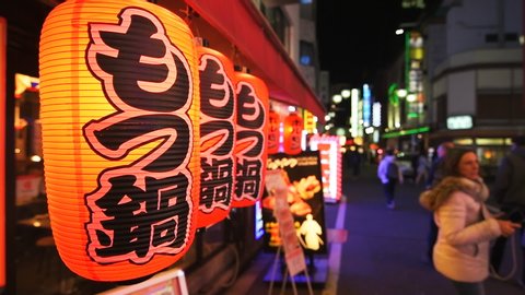 Shinjuku, Japan - April 3, 2019: Slow motion of famous Kabukicho narrow alley street red light district in Tokyo city with illuminated night paper lanterns by izakaya motsunabe restaurant or pub