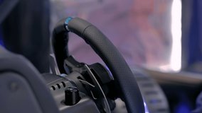 Woman gamer hand using black gaming steering wheel joystick and playing in car drive simulator at modern technology exhibition. Entertainment, hobby, technology and leisure time concept