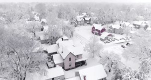 Small town neighborhood, homes blanketed in deep winter snow, aerial view after blizzard, aerial drone view.