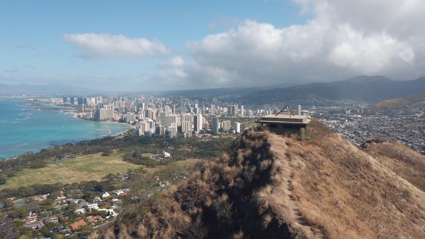 Scenic view of Honolulu from the famous Diamond Head crater. City skyline along the clear blue water backed by steep mountains and clouds building. Incredible beauty of Hawaii.