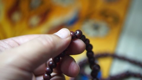 Footage of prayer beads being count in a man's hand