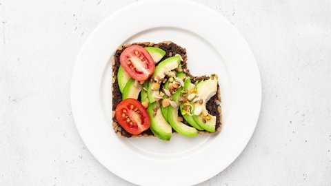 Stop motion animation of eating vegan food avocado toast bite by bite. Top view. Healthy eating concept