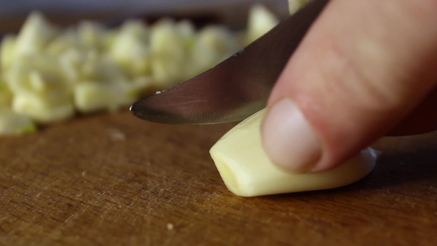 male hands cut garlic on a wooden board. close-up