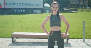 Workout Young woman doing sports in outdoors modern place in city park in summer sunny day under sun light. 4K slow motion video

