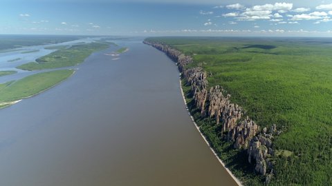Helicopter epic flight Russia Lena pillars rocks formation crag. Widest river bed Lena attraction Yakutsk Sakha republic. Taiga green forest. Summer sunny blue sky clouds horizon 4K