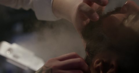 Barber cutting client beard with straight razor in Barbershop slow motion 4k