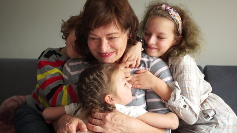 Grandmother posing with grandchildren. Two girls and one boy. Happy children hug their grandmother, portrait of Indoor. Two generations, a large family, a grandmother and grandchildren
