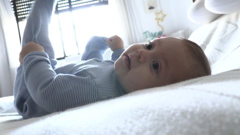 Baby toddler layed in bed looking to camera