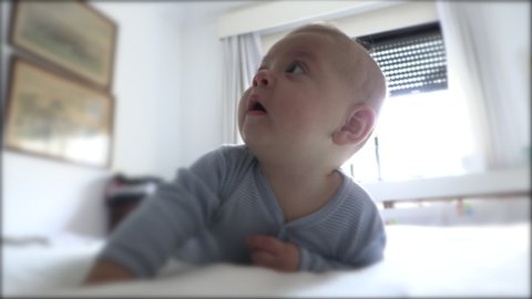 Cute adorable baby infant in bed observing