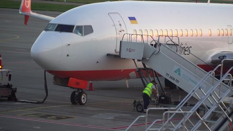 BORISPOL, UKRAINE - JUNE 2019: Airport technicians connect a ramp to the doors of a landing passenger plane