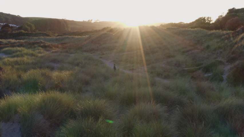 Drone Shot Of Children Playing In Sand Dunes On Winter Beach As Sun Sets
