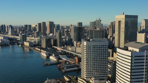 Aerial view of cityscape of Tokyo at sunrise, waters of Tokyo Bay and skyscrapers skyline of modern Japanese capital city, clear blue sky - landscape panorama of Japan from above, Asia