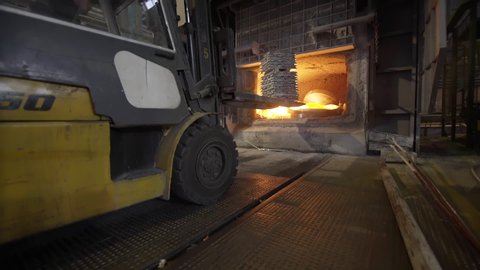 Loader loads aluminum ingots into a blast furnace. Aluminium foundry furnace loaded with metal. Red hot flames glowing and liquid melting.