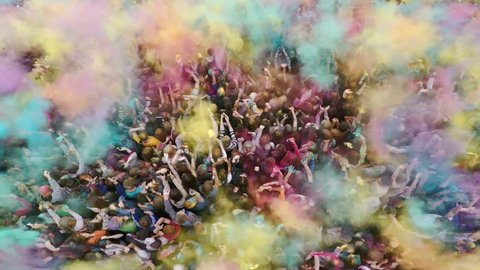 Aerial flight above dancing crowd on Holi Festival Of Colors. Crowd of people colored powder and having fun. Russia, Chelyabinsk, 13 June 2015