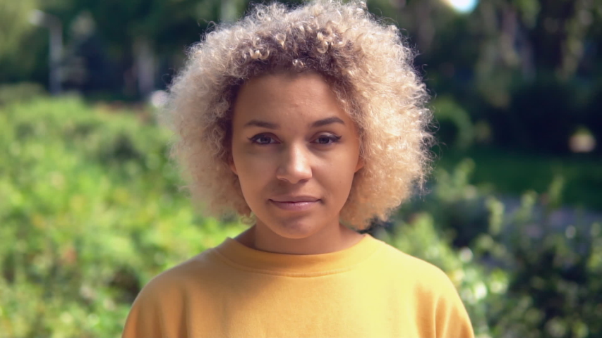 close up portrait mixed race woman looking camera happy smiling on the background green trees slow motion