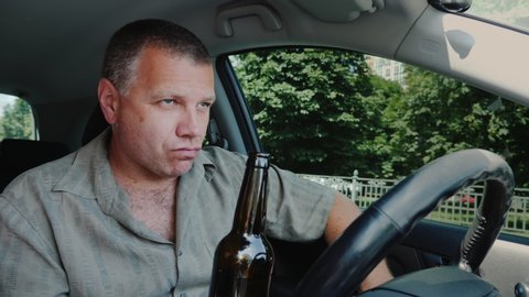 A rude man drinks alcohol in the car. Drunk driving