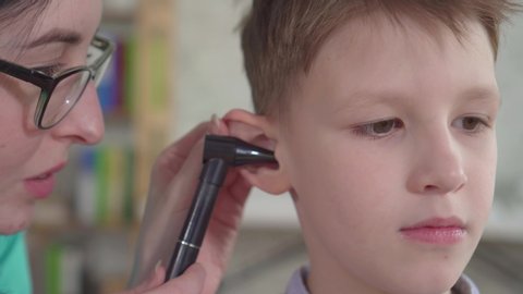 An otolaryngologist examines the ears of a little boy close up