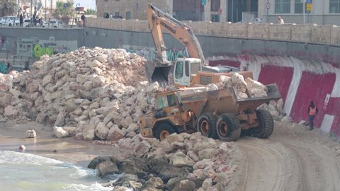 Tel Aviv - December 4th 2019: Construction work at a city beach, by the old Jaffa port. Dump truck clearing a load of dirt and big stones from the site.