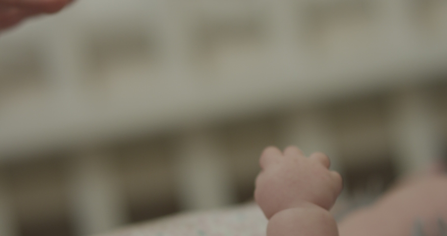4K Closeup shot of baby's little cute hand reaching for father's loving finger . Baby holding parent's finger. Parent holding newborns hand in Slow Motion. Hand in hand. Father and newborn baby .  Royalty-Free Stock Footage #1042622728