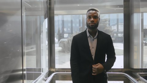 Young confident afro-american bearded lawyer entering elevator of business center going to meet his client