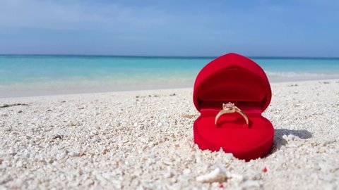 Open Heart Shape Red Box with Wedding Proposal Ring Laying On White Sand beach in Caribbean