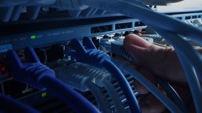 Macro Shot: IT Administrator Plugs in RJ45 Internet Connector into LAN Router Switch. Information Communication Network in Data Center with Cables Connected to Modem Ports with Blinking Lights - Powered by Shutterstock - Get 15% off with code: PIKWIZARD15