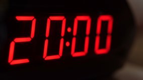 Close-up of black digital clock screen showing 20.00. Blinking red digital numbers on black background. Modern timer system and neon light, electric alarm device
