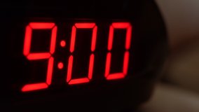 Close-up of black digital clock screen showing 9.00. Blinking red digital numbers on black background. Modern timer system and neon light, electric alarm device