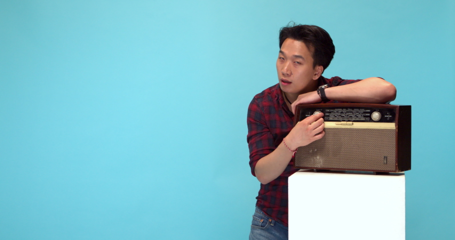 Studio, slow motion, young man turns on a vintage radio