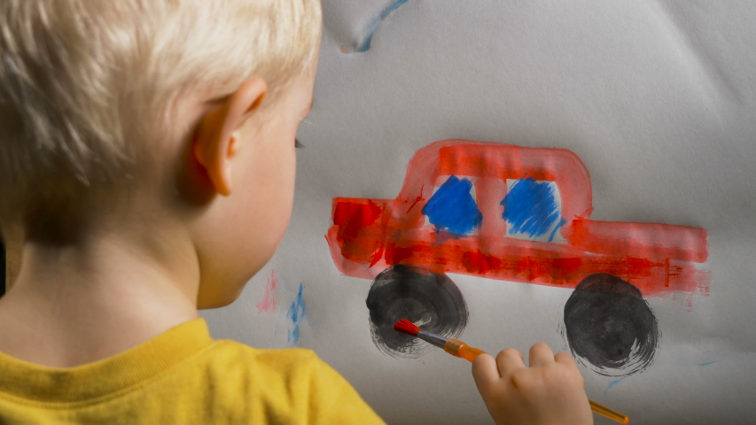 Little boy (preschooler) is painting a red toy truck with acrylic paint. Indoor kids activities, daycare, classroom. Early education concept, child creativity and art Royalty-Free Stock Footage #1042655647