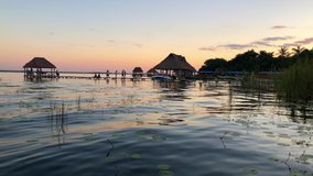 4k View of Bungalows on a Dock in Lago Bacalar with a Stunning Colorful Sunset