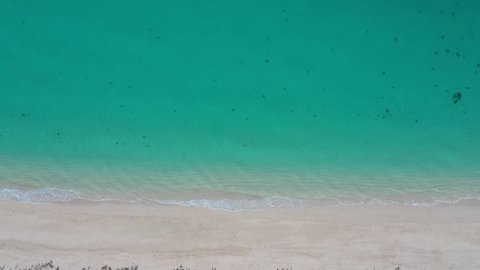 Drone footage of sea water lapping on sandy beach 
