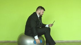 A caucasian man with a beard office worker talking on the phone via video link and playing sports, green background, chromackey