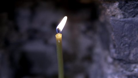 Close-up of a candle burning in an old Church. Footage. Close up beautiful burned candles on dark gray wall background