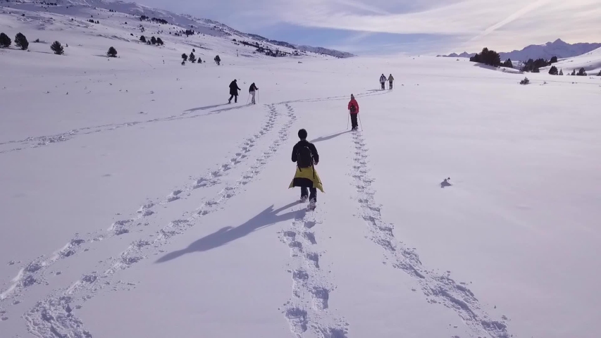 AERIAL FOLLOW SHOT OF FRIENDS WALKING IN SNOW