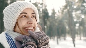 slow motion Winter portrait of funny smiling woman in woolen hat and long warm scarf in snowy winter park at frozzy sunny day. woman exhales steam and wraps herself in a scarf. Happy winter time - Powered by Shutterstock - Get 15% off with code: PIKWIZARD15