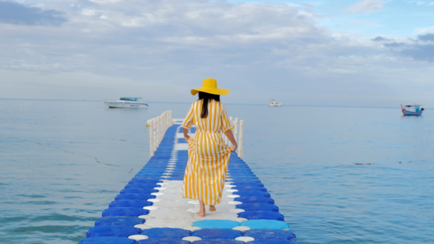 Woman walking on plastic pontoon walk way floating in the sea  and looking to a sky.