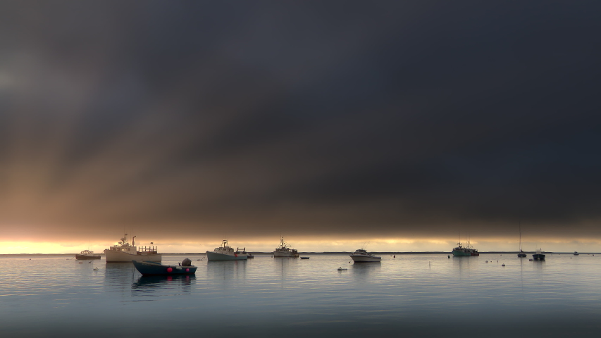 Fishing boats moored in a cove at sunset on Cape Cod in Massachusetts. Seagulls and birds fly overhead.