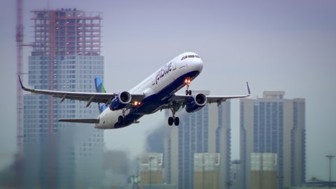 BOSTON, MA - CIRCA 2019: A Jet Blue passenger jet takes off from Boston’s Logan airport with the city skyline and other jets in the background. Slow motion.