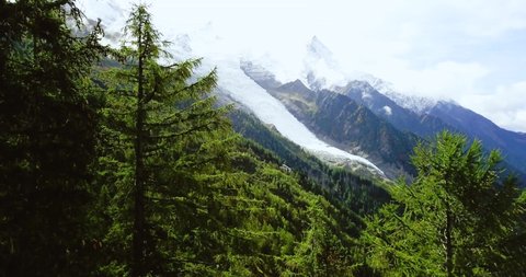 French Alps Mountains. Mont-Blanc Foggy landscape. Snowy peaks in Chamonix. Swiss rustic scene. Panoramic aerial view of the valley. Pine forest. Footage for advertising and web. 4K drone shooting.