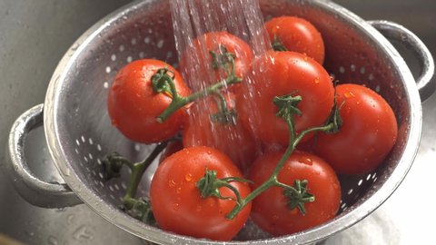 Washing organic vine ripened tomatoes in a stainless steel colander.
