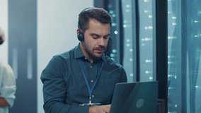 IT support engineer hosting on laptop computer at server racks, talking with head office on headphones, coworking in team at database cyber security. - Powered by Shutterstock - Get 15% off with code: PIKWIZARD15