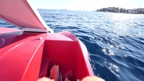Male, men twists her feet pedals catamaran swimming sport facility for relaxing walks on sea water. Male hairy bare legs pedal on double catamaran. Catamaran swims towards shore. Slow motion video.