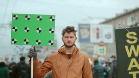 Man hold banner in hand. Tracking points for copy space. Blank green screen board. Human rights. Crowd people day demonstration. Rebel strike protest. Revolution in city street. Political rally 4k. - Powered by Shutterstock - Get 15% off with code: PIKWIZARD15