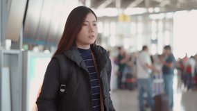 4K handheld video clip with pretty traveler female checking bag on her back to finding passport at airport terminal, she smiling with happiness and hold it in hand before walking forward