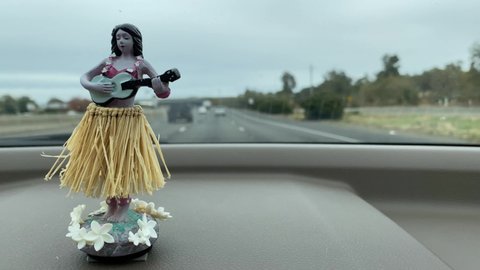 Citrus Heights, CA - November 20, 2019: Hawaiian hula hoop dancer air freshener on dashboard while driving on freeway. 