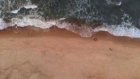Aerial view A video of a tropical beach at sunset showing evening aerial footage of green foaming ocean waves crashing onto the coastline. Top view without people
