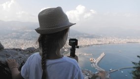 Child girl traveller with camera shooting video cityscape Alanya city, Turkey at viewpoint.