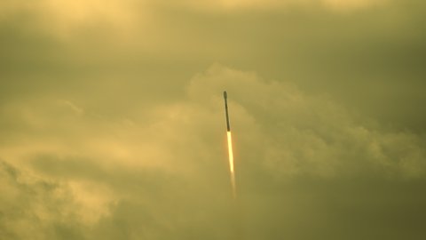 Rocket flies through the cloudy sky at sunset as it climbs towards space with a  commercial satellite payload to orbit in space. Dramatic lighting. Slow motion. : vidéo de stock