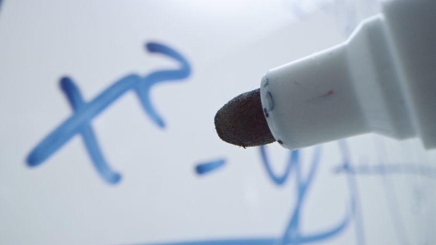 Macro Follow Shot of a Blue Marker Pen Being Held with a Hand. Teacher Writing Equations on a Whiteboard with Mathematical Formulas. Pencil is Connected to the Camera. Gripped Shot. Royalty-Free Stock Footage #1042774708